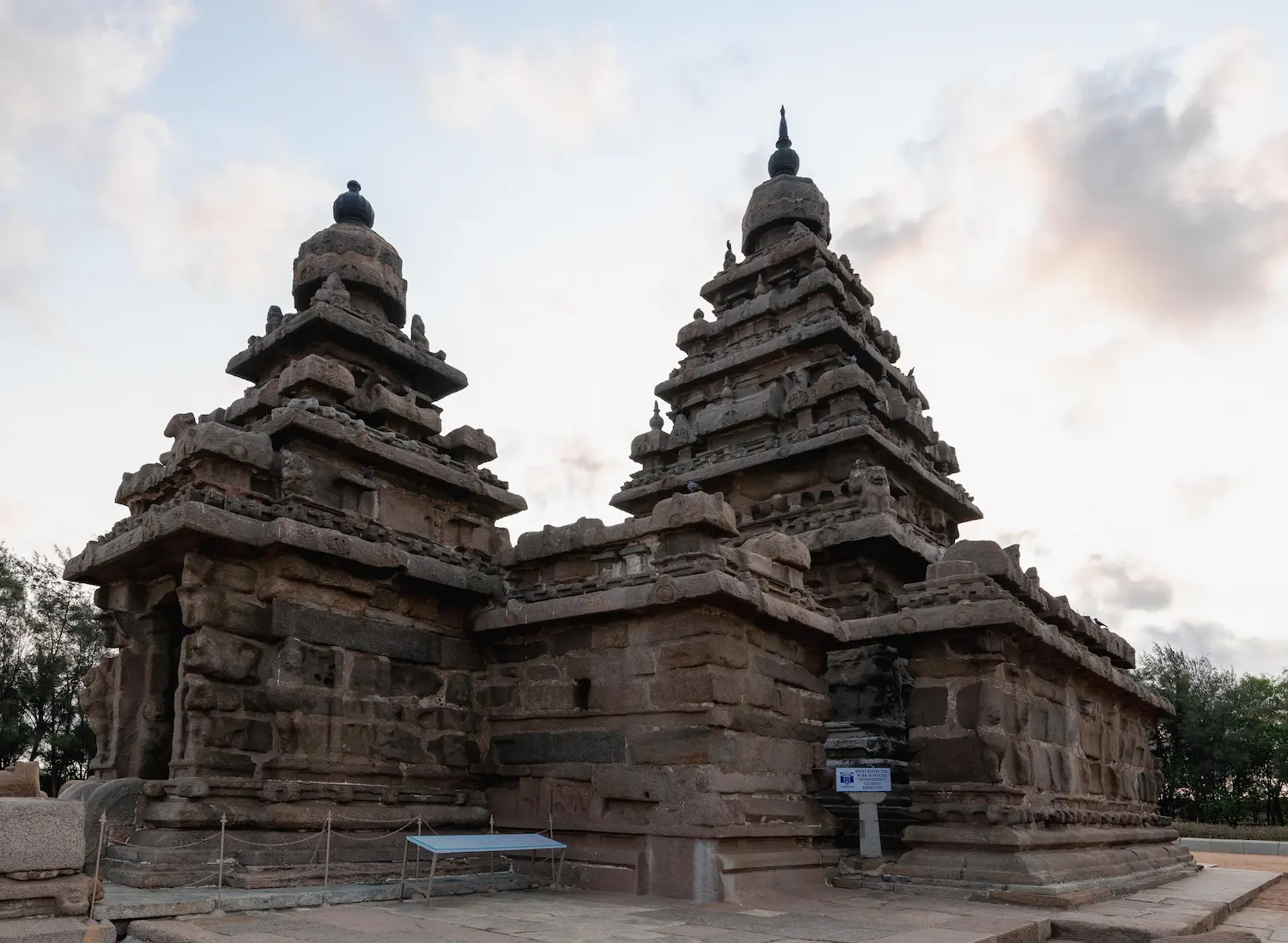 Pallava-era granite Shore Temple lit up by soft early morning sunlight on the Bay of Bengal coast in Mahabalipuram.