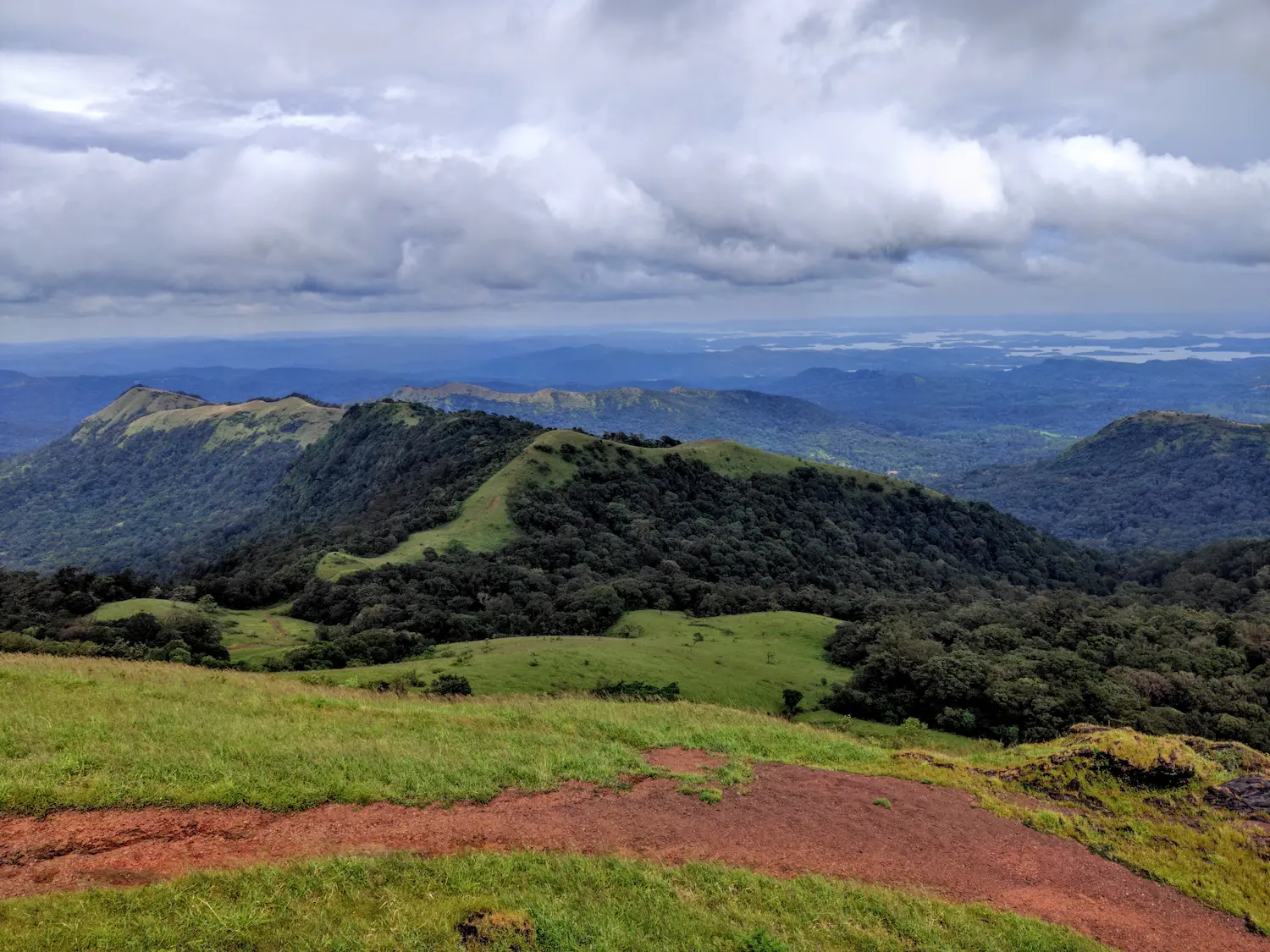 Panoramic view of the rolling green Western Ghats peaks and winding mountain road near Mullayanagiri, Chikmagalur.